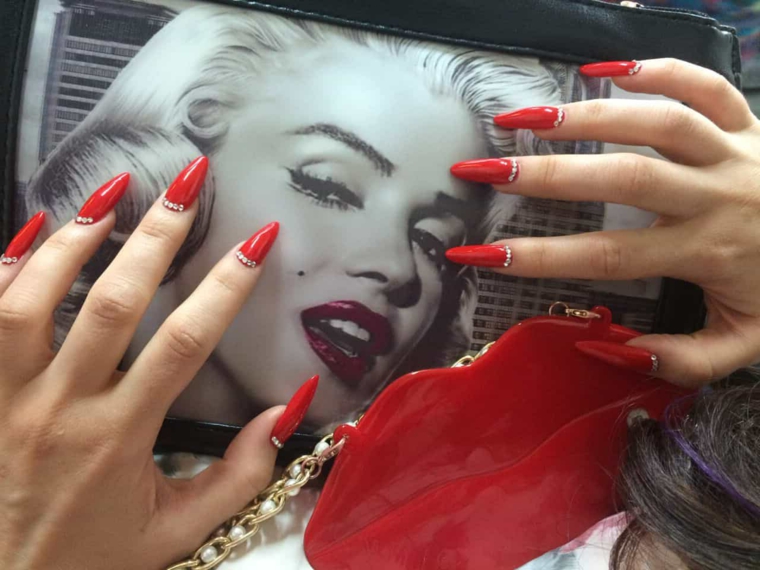 Nail art unghie a punta di colore rosso e brillantini incollati con gel nella parte superiore dell'unghia 