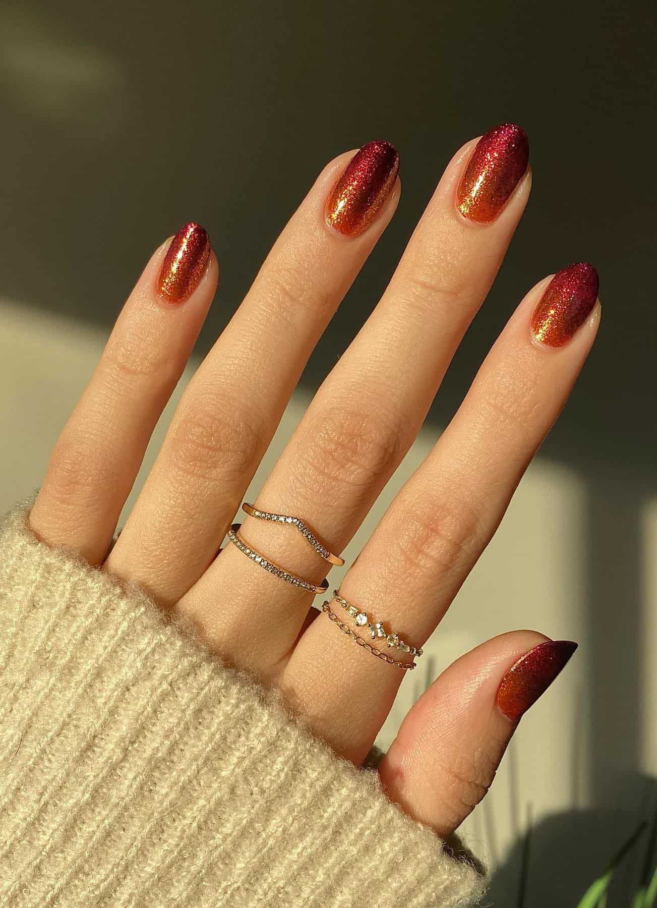 a hand with short round nails painted an orange and red glitter ombre